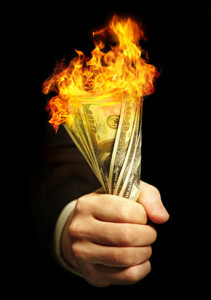 man's hand holds  dollars on fire